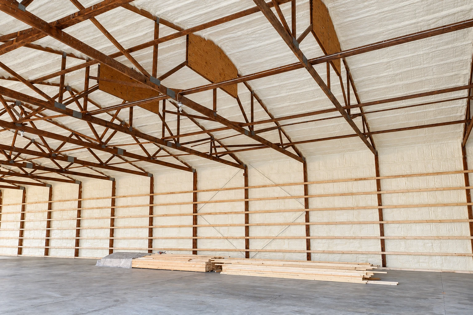 A large timber-framed building with white spray foam insulation covering the roof and walls.